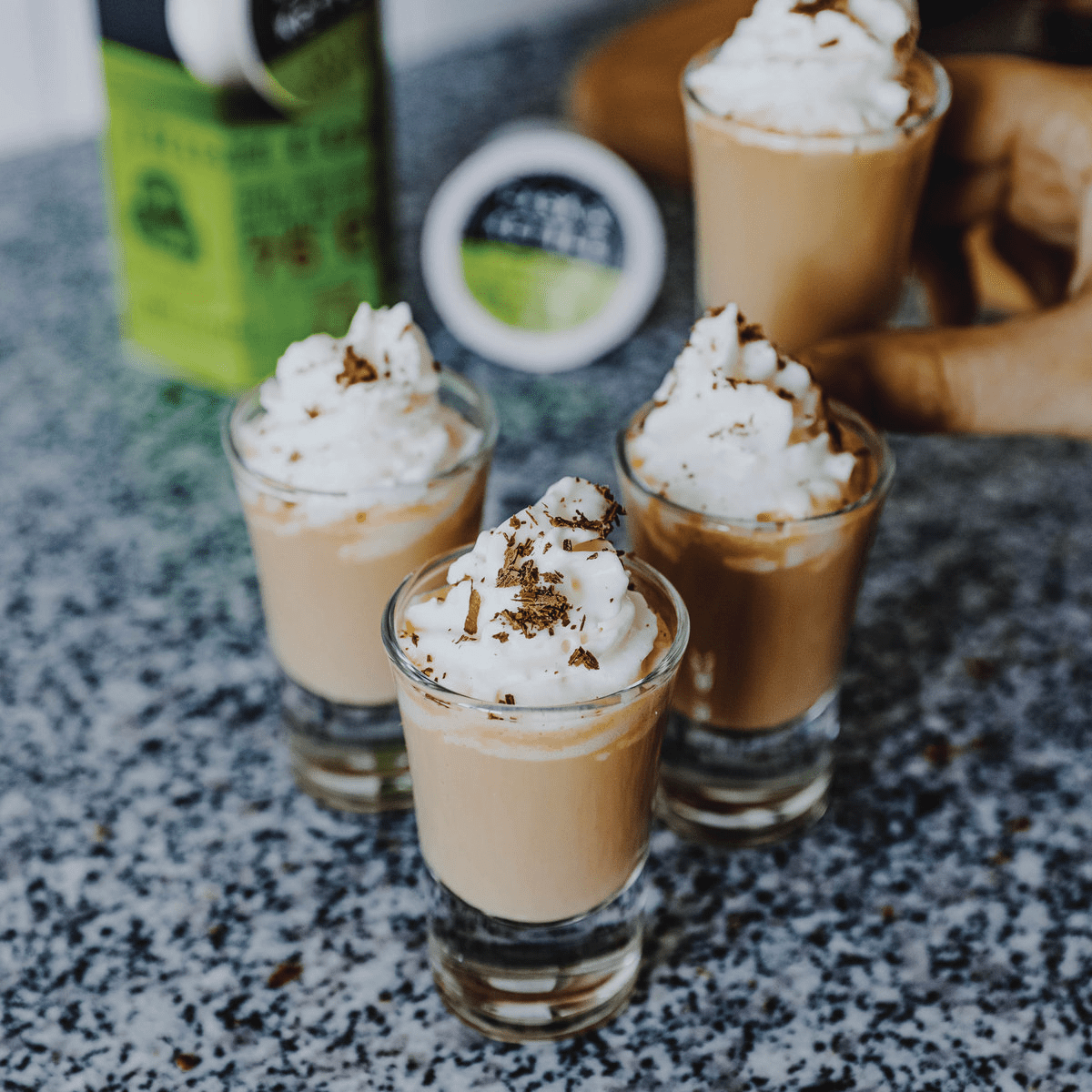 four shot glasses with Irish Coffee and whipped cream
